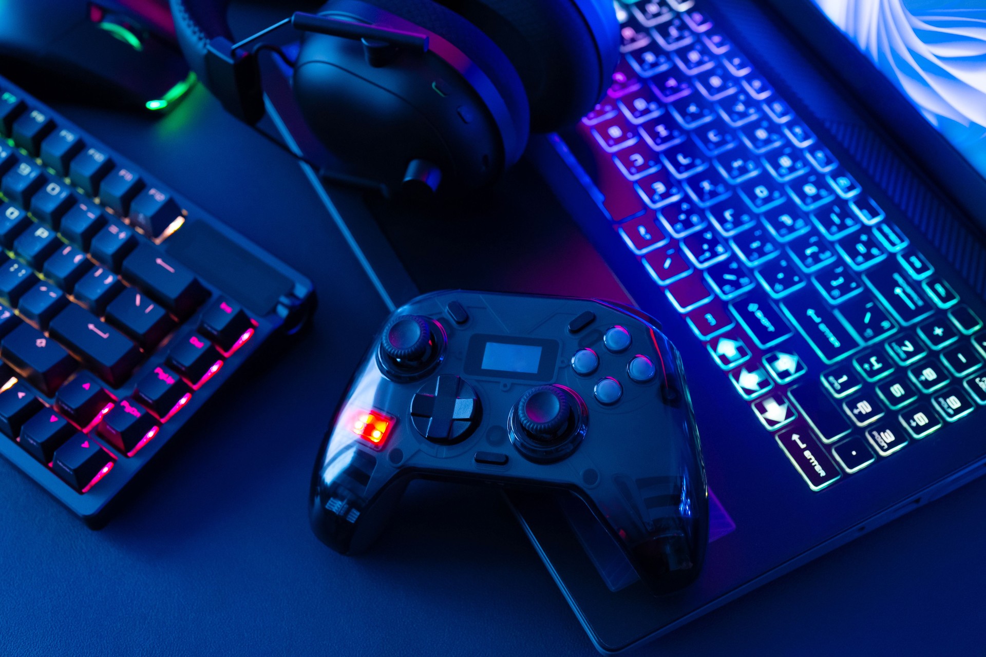 gamer work space concept, top view a gaming gear, mouse, keyboard, joystick, headset, mobile joystick, in ear headphone and mouse pad on black table background.